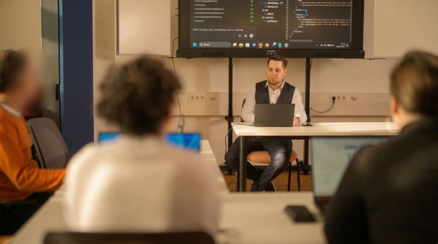 Christian Vogel gibt eine KI-Schulung vor einer Gruppe mit Laptops